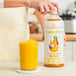 A person pours Smartfruit Aloha Pineapple Puree into a jar.