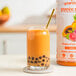 A bottle of Smartfruit Tropical Harmony puree next to a glass of tropical fruit.