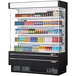 A Turbo Air black vertical air curtain display case with drinks and beverages on shelves.