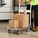 A person pushing a Lavex aluminum platform truck with boxes on it.