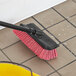 A Lavex bi-level floor scrub brush with a squeegee on a tile floor.