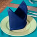 A folded royal blue polycotton blend Intedge cloth napkin on a plate.
