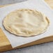 A round dough on a wooden board.