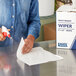 A woman using a Lavex industrial wiper to clean a table.