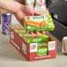 A hand holding a box of JJ's Bakery Apple Pie Turnovers.