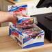 A hand holding a package of Hostess Chocolate Frosted Mini Donuts.