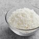 A bowl of Unsweetened Coconut Flakes on a gray surface.