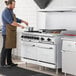 A man in a brown apron cooking on a Main Street Equipment commercial range with griddle and ovens.