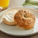 A Just Bagels everything bagel with cream cheese on a plate.