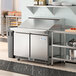 An Avantco sandwich prep table on a stainless steel counter in a commercial kitchen.
