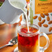 A person pouring Pacific Foods Organic Almond Milk into a glass of liquid.