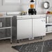 A stainless steel kitchen with an Avantco worktop refrigerator on a counter.