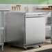 A stainless steel undercounter freezer with a single solid door and front ventilation.