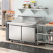 An Avantco VersaHub 2 door refrigerated sandwich prep table on a stainless steel counter.