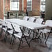 A white Lifetime folding table with white chairs set up in a room.