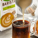 A spoon pouring Pacific Foods Barista Series soy milk into a cup of coffee.