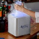 A person using an Avantco countertop glass froster on a counter in a cocktail bar.