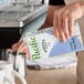 A carton of Pacific Foods Barista Series Vanilla Soy Milk being poured into a metal frothing pitcher.