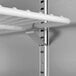 A white metal shelf for a VersaHub Freezer with a metal bar attached to it.