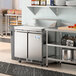 An Avantco 2 door front breathing cutting top refrigerated sandwich prep table in a commercial kitchen.