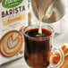 A person pouring Pacific Foods Barista Series almond milk into a glass of coffee.