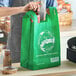 A man holding a green Inteplast Group reusable T-shirt bag.