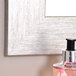 A BrandtWorks silver grain finish mirror reflecting a pink bottle of liquid.