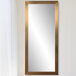 A BrandtWorks champagne finish mirror with gold trim on a white wall.