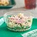 A Stalk Market clear plastic deli container filled with rice and vegetables on a green surface.