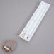 A white rectangular wall thermometer with a wire.
