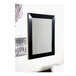 A BrandtWorks black rectangular mirror with a white screen on a wall.