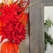 A hand holding a vase with red flowers and leaves reflected in the BrandtWorks Barnwood Gray Finish Mirror.