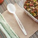 A white plastic Stalk Market CPLA spoon in a plastic container of salad.