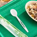 A white Stalk Market CPLA spoon next to a bowl of rice and beans.