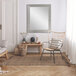 A BrandtWorks silver grain finish mirror on a white wall over a vase of flowers.