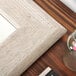 The corner of a BrandtWorks wood frame mirror with a jar of flowers in front of it.