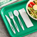 A green tray with a white knife and fork and a bowl of salad.