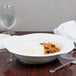 A CAC white porcelain bowl filled with pasta on a table.