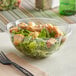 A Stalk Market clear PLA salad bowl filled with salad and a black fork on a napkin.