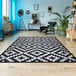 A black and white Couristan Afuera Diatomic area rug in a room with a chair.