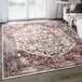 An Abani Lola Collection terracotta area rug with a vintage medallion design in a room with a white wall and black trim.