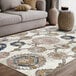 An Abani Arto Collection coral and navy area rug with a distressed medallion design next to a couch.