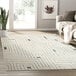 A cream and gray Abani Cabo Collection geometric labyrinth area rug on a floor.