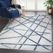 A blue and gray Abani Atlas Collection area rug with criss cross lines in a room.