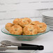 A green glass bowl filled with bagels on a table.