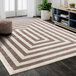 A beige and cream rectangular area rug with a striped pattern in a white room.