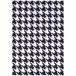 A cream area rug with a black and white geometric houndstooth pattern and white border.