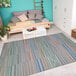 A Couristan ivory, multi-color, and blue striped area rug in a white room with a bed.