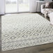 An Abani Casa Collection cream and gray Moroccan area rug with a geometric pattern on the floor in a room with white walls.