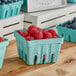 A green Pactiv berry basket filled with raspberries and blueberries.